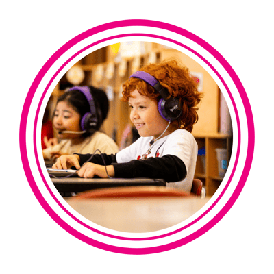 1st grader wearing headphones smiling at tutor on computer screen